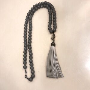 Silver beaded necklace with tassel pendant, shiny details on beads